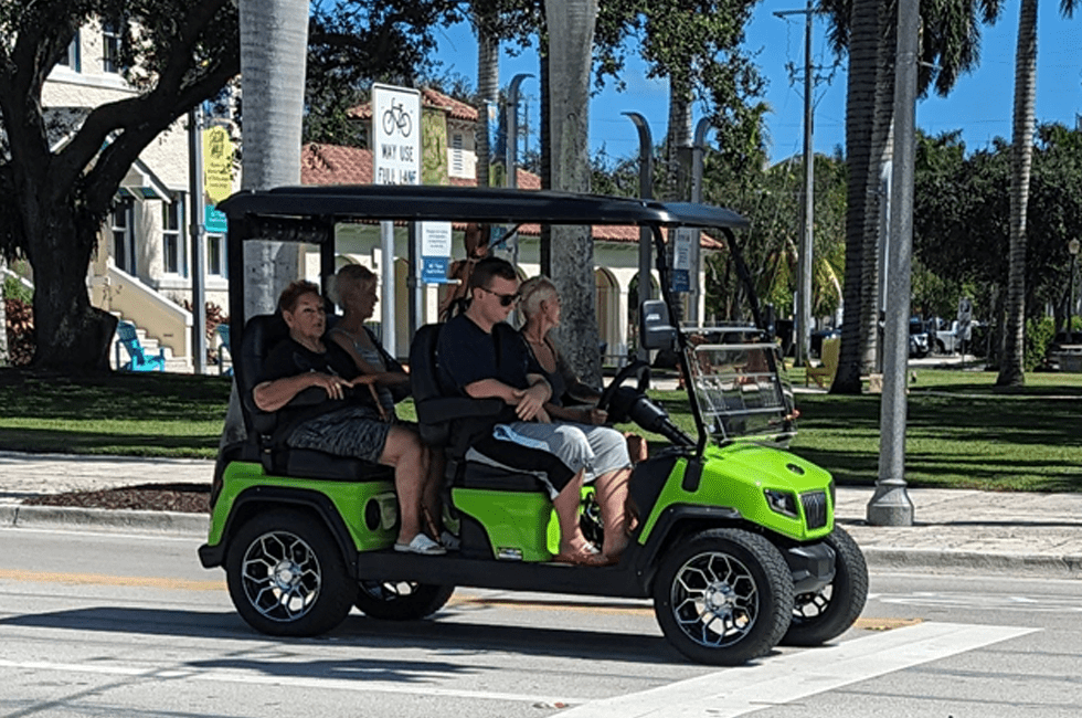 People in a golf cart driving down a Delray Beach street | Golf Cart Accident Lawyer