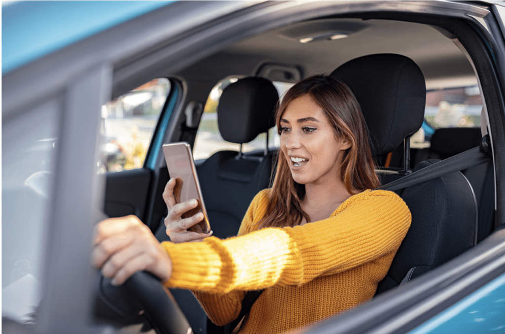 A young woman, in car with mobile phone