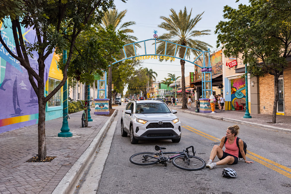 Woman beside a fallen bicycle after an accident in Delray Beach’s Pineapple Grove Arts District.